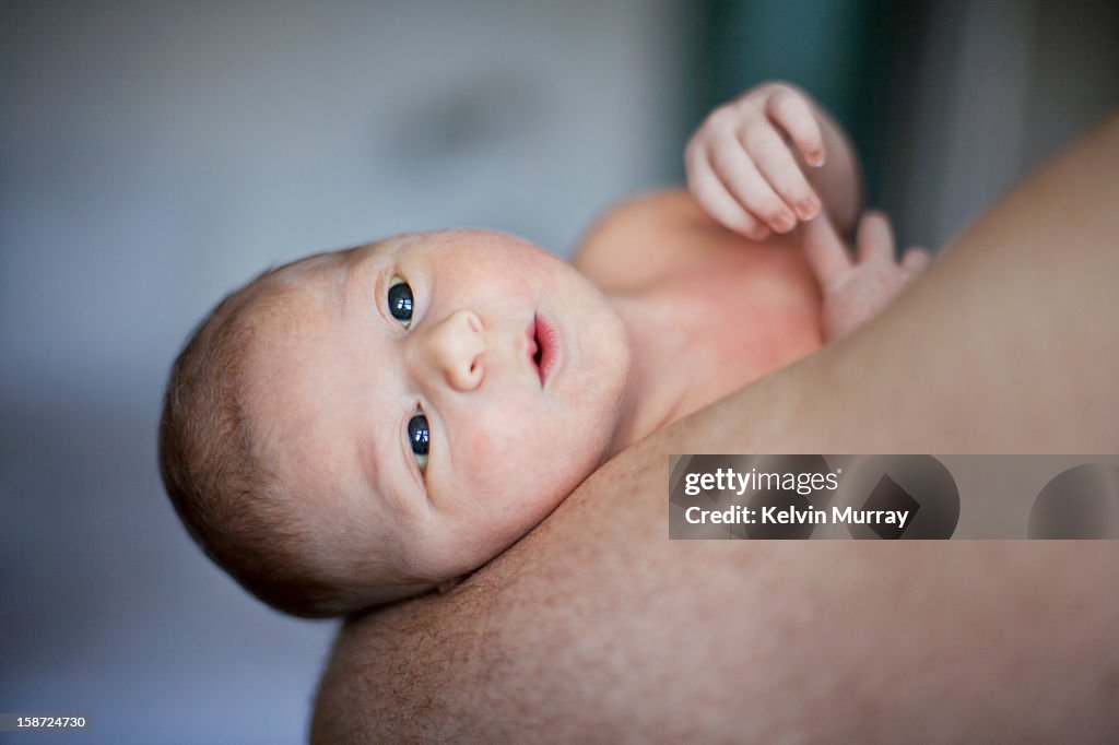 Newborn baby lying in fathers arms