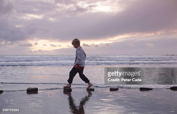boy walking over stepping stones sea - stepping stones stockfoto's en -beelden