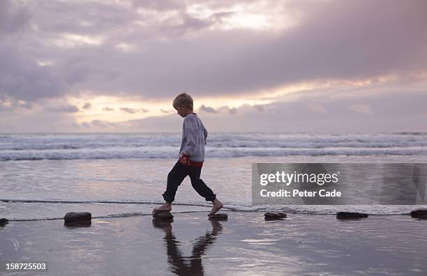 boy walking over stepping stones sea - stepping stone stock pictures, royalty-free photos & images