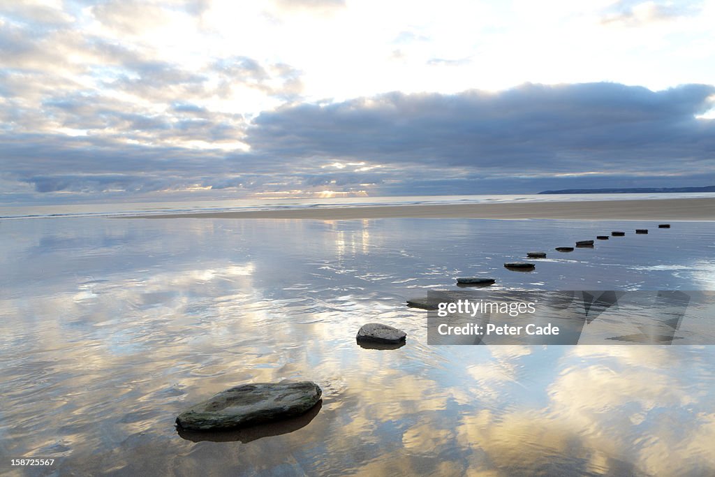 Stepping stones over water with sky reflections