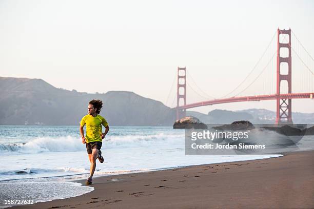 a man running during sunset. - baker beach stock pictures, royalty-free photos & images