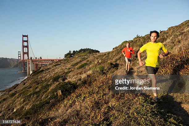 two men running during sunset. - baker beach stock pictures, royalty-free photos & images