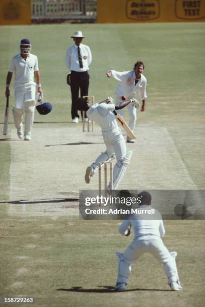 Norman Cowans of England loses his helmet as he tries to dodge a bouncer bowled by Dennis Lillee of Australia during the Ashes First Test on 13th...