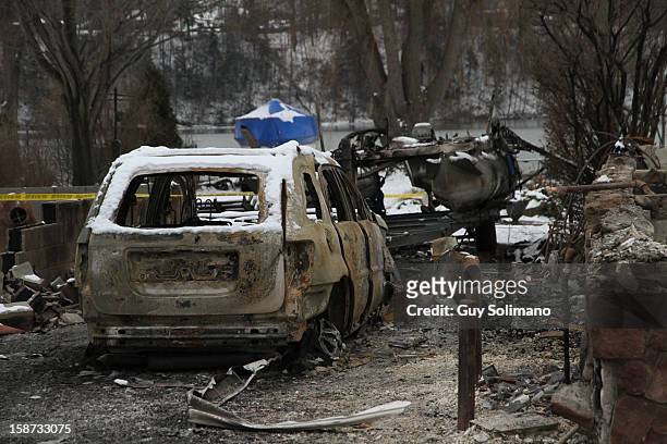 The burned out shell of a car sits in the rubble at the site of the Christmas eve shooting and fires on Wednesday, December 26, 2012 in Webster, New...