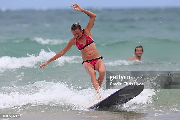 Slovakian tennis player Daniela Hantuchova stands up during a surf lesson with pro surfer Julian Wilson at Coolum Beach on December 27, 2012 in...