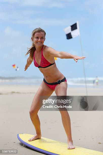 Slovakian tennis player Daniela Hantuchova stands up during a surf lesson with pro surfer Julian Wilson at Coolum Beach on December 27, 2012 in...