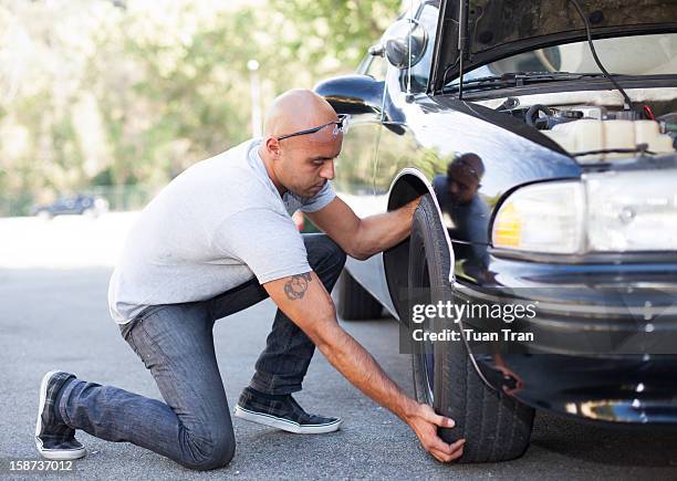 man changing tire on car - vornüber beugen stock-fotos und bilder