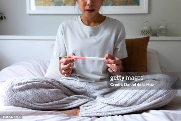 unrecognizable young woman disappointed to see negative pregnancy test in bedroom. young female worried after checking positive pregnancy test. - unusual imagens e fotografias de stock