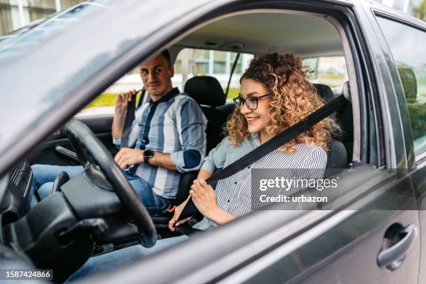 driving instructor and a female student fastening their seatbelts - new driver stock pictures, royalty-free photos & images