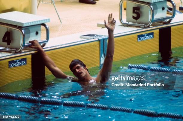 American swimmer Mark Spitz greets the public, pointing three with his fingers, after having won the 200 metres freestyle final and conquered the...