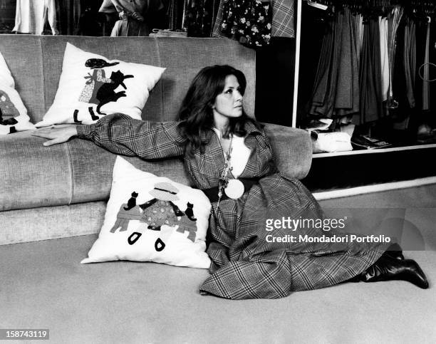 Italian actress and TV presenter Laura Efrikian sitting on the floor and leaning on a sofa. Rome, 1970s
