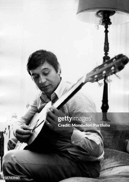 Fred Bongusto , Italian pop-music singer, performs a guitar solo seated on the sofa in his Roman house in Via del Nuoto. Rome, October 1967.