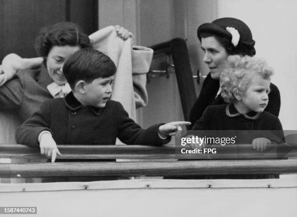 British Royals Prince Charles of Edinburgh and his sister, Princess Anne of Edinburgh, with their nannies in the background, on board the Royal Yacht...