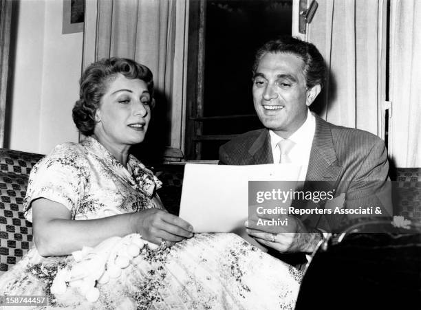 The US actor Robert Alda and the Italian actress Andreina Pagnani are seated next to the other and are reading a page of a script. Italy.