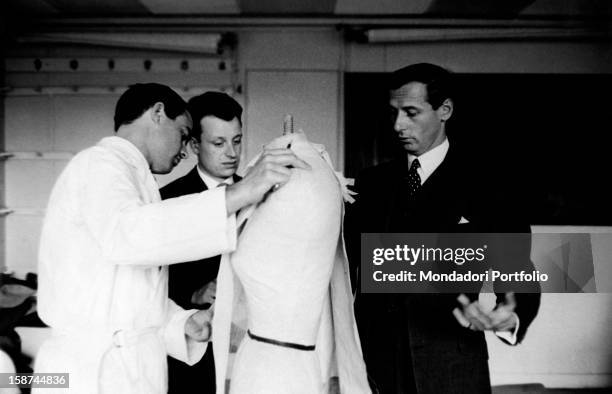 French stylist Marc Bohan, director of the fashion house Dior, watching a tailor working. 1960s