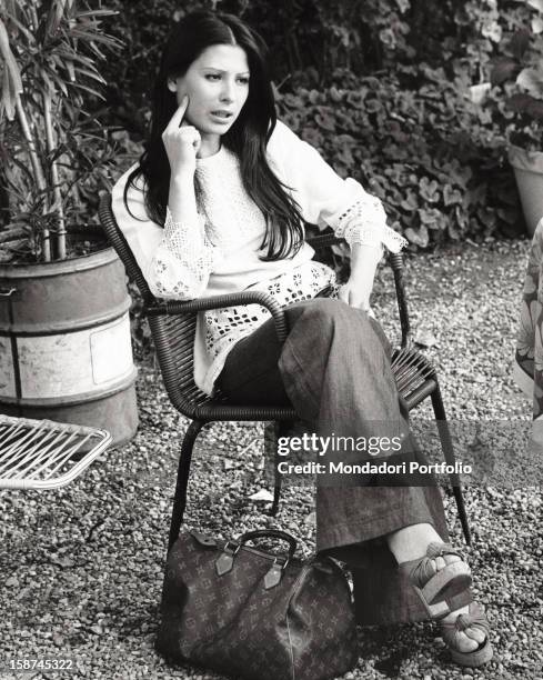 Portrait of the Italian singer and actress Rosanna Fratello sitting on a chair in a garden. Casalpusterlengo, 1974