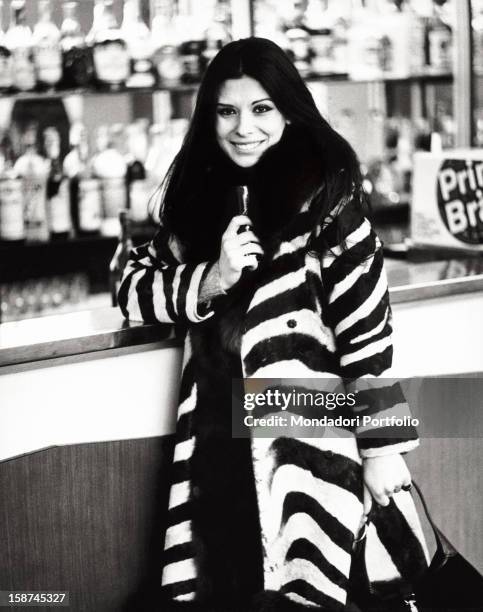 Portrait of the Italian singer and actress Rosanna Fratello leaning on the counter of the bar of Palazzo del Ghiaccio. Milan, 1972