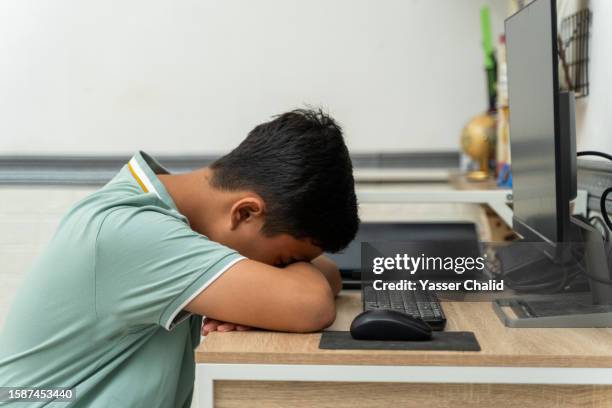 teenage boy sitting at desk hiding his face - one teenage boy only fotografías e imágenes de stock