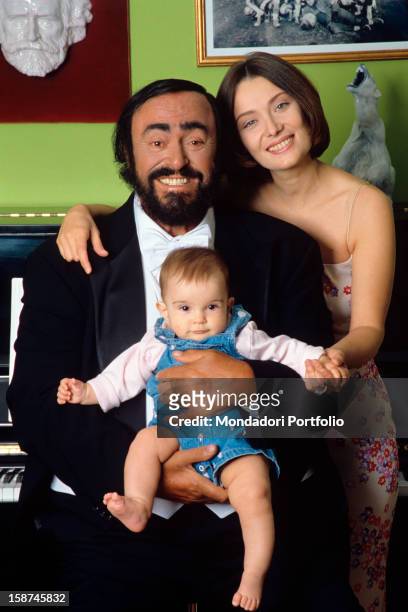 The Italian opera singer Luciano Pavarotti poses smiling for the photographer, holding his daughter Alice in his arms and with his second wife...