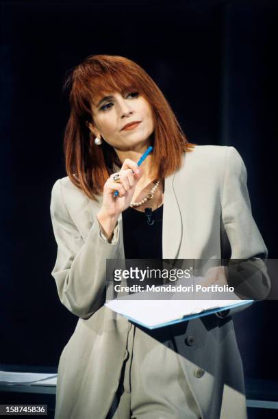 The Italian journalist Lilli Gruber, born Dietlinde Gruber, holds a folder in her hand and holds her right hand close to her chin while listening...