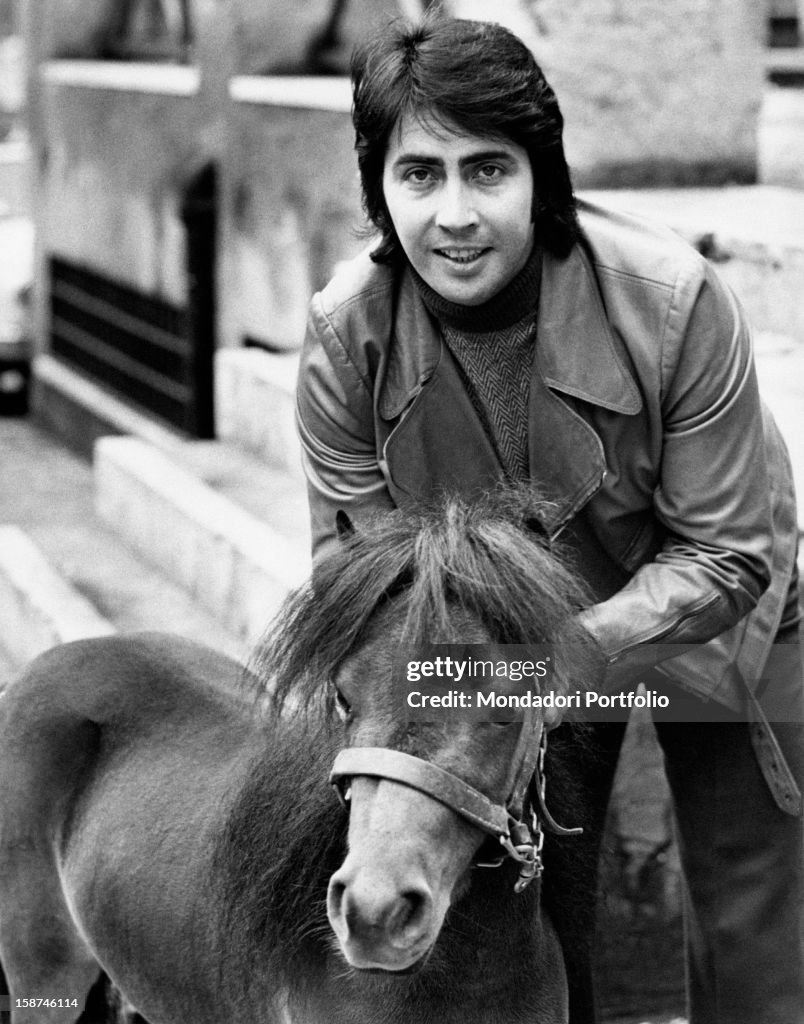 Italian singer and actor Lando Fiorini stroking a pony. Rome, 1970s