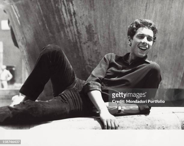Italian actor Gabriele Lavia lying on the ground and smiling. Rome, 1970s