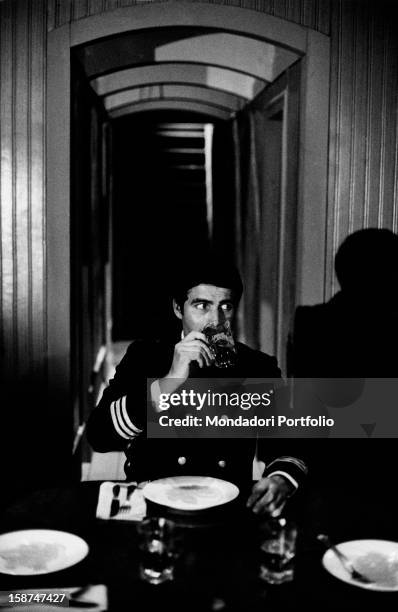 Italian actor Nino Castelnuovo sitting at a table and drinking in the TV movie L'ospite segreto. June 1967