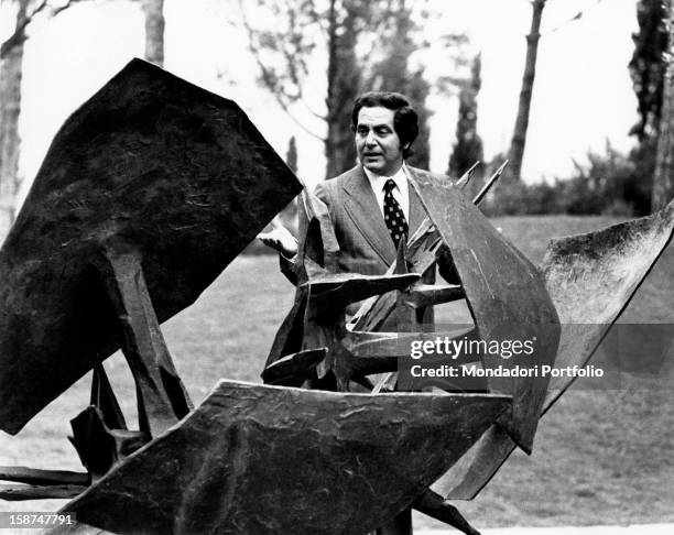Italian TV host Corrado looking at a sculpture. Rome, 1970s