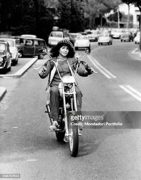 Italian actress and singer Maria Grazia Buccella riding a motorcycle. Rome, 1970s