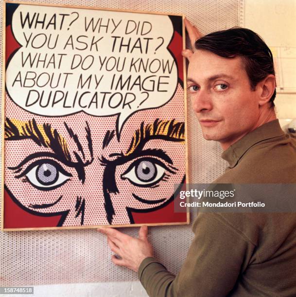 The American painter and representative of Pop Art Roy Lichtenstein shows one of his paintings, looking satisfied. 1964.