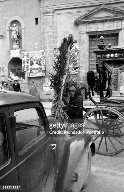 Sicilian man carrying a funeral wreath. Sicily, March 1958