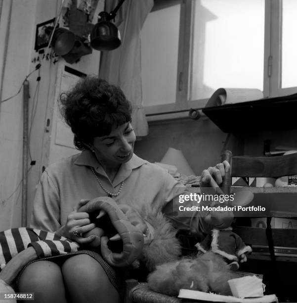 Italian artist and puppet maker at work and joking with Topo Gigio, one of her puppets. Milan, 1960s