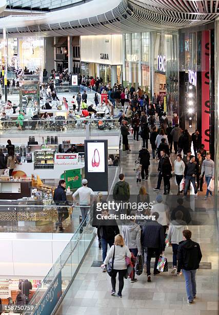 Shoppers pass clothing stores and food outlets as they walk through the Westfield Stratford City shopping mall in London, U.K., on Thursday, Dec. 27,...