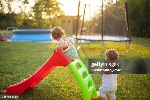 des jumeaux sur un toboggan à l’aire de jeux - toboggan photos et images de collection