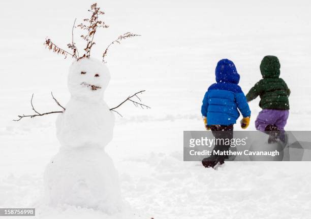 Two girls run through past their snowman on December 27, 2012 in Greenfield, Massachusetts. A serious winter storm that caused tornados in the South...