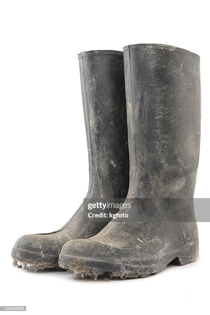 Dirty black gumboots on white background