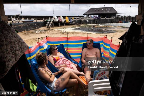 Friends enjoy a break in the weather outside their beach hut on August 02, 2023 in Broadstairs, United Kingdom. August 2023 in the UK has seen...