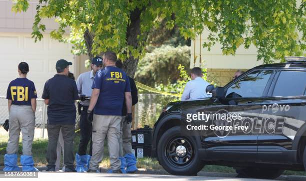 Officials and other law enforcement officers stand outside the home of Craig Robertson who was shot and killed by the FBI in a raid on his home this...