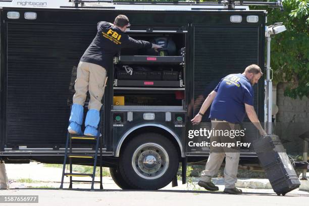 Officials unloads the equipment as they process the home of Craig Robertson who was shot and killed by the FBI in a raid on his home this morning on...