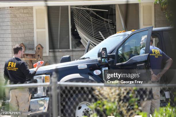 With a broken window in the background, FBI agents process the home of Craig Robertson who was shot and killed by the FBI in a raid on his home this...