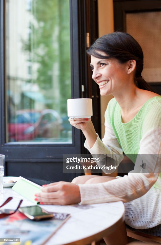 Woman using digital tablet at a café, smiling