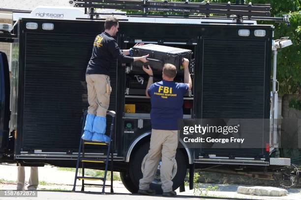 Officials unload the equipment as they process the home of Craig Robertson who was shot and killed by the FBI in a raid on his home this morning on...