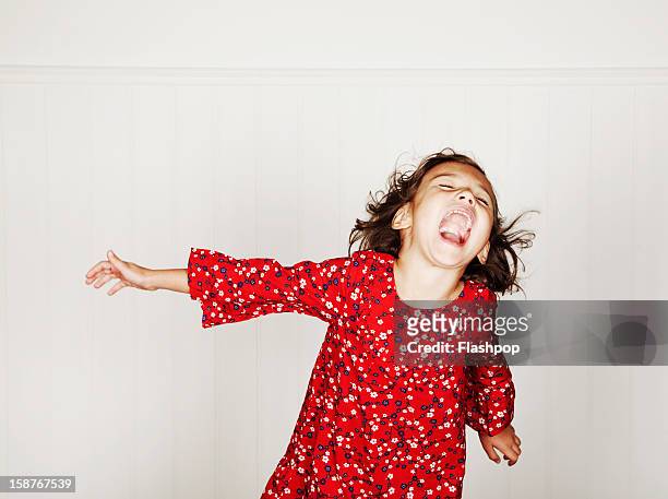 portrait of girl pulling funny faces - red dress child stock-fotos und bilder