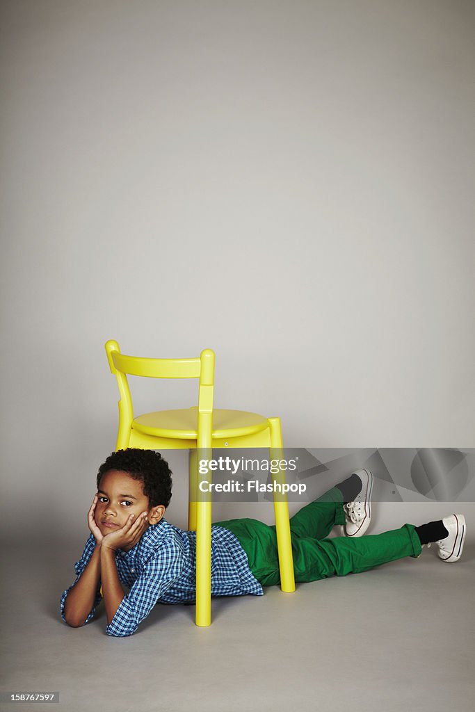 Portrait of boy with chair pulling funny faces