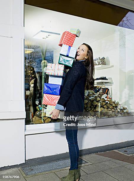young woman carrying gift packs infront of shop - carrying gifts stock pictures, royalty-free photos & images