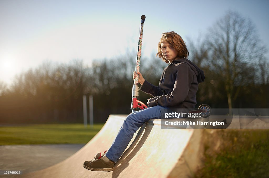 Young boy sitting on ramp at skate park.