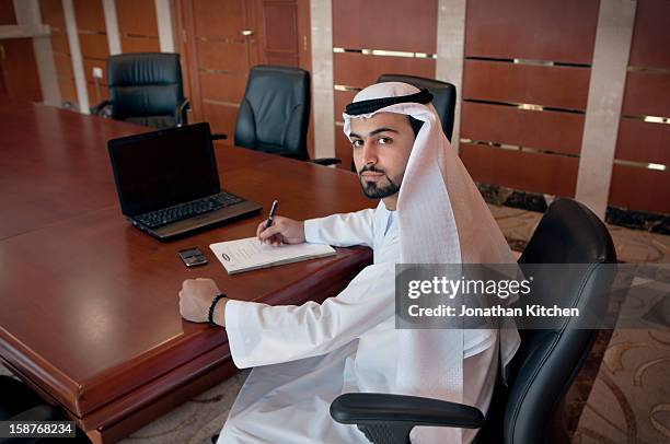 middle eastern man at a desk doing business 2 - emirati guy using laptop stock-fotos und bilder