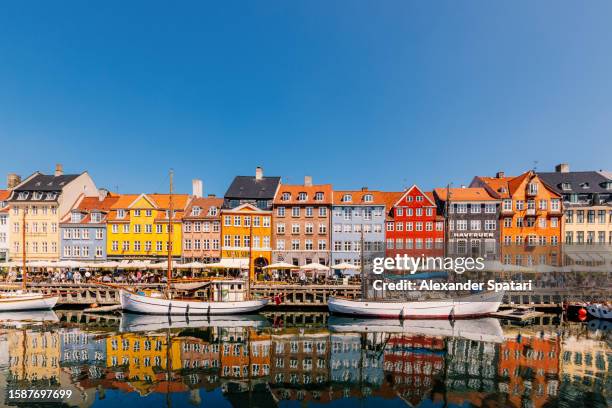 multi-colored vibrant houses along nyhavn harbour on a sunny day with clear blue sky, copenhagen, denmark - northern europe foto e immagini stock