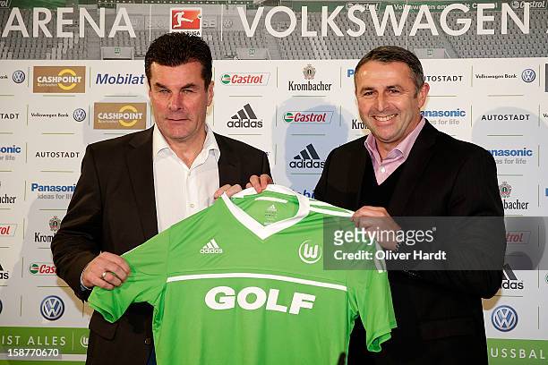 Sporting director Klaus Allofs of Vfl Wolfsburg presents a team jersey to new head coach Dieter Hecking during a press conference at Volkswagen Arena...