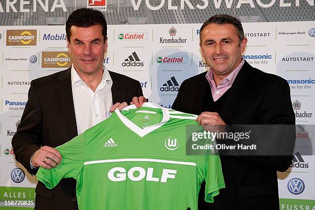 Sporting director Klaus Allofs of Vfl Wolfsburg presents a team jersey to new head coach Dieter Hecking during a press conference at Volkswagen Arena...